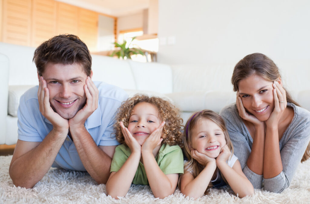 A Smiling Family Lying on Clean Carpet